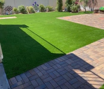 A backyard with fake grass and paver stones